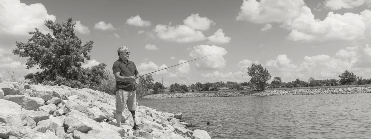 Steve fishing on a lakeshore while wearing his Harmony prosthesis