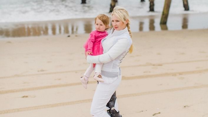 Kseniya standing on a beach holding her daughter