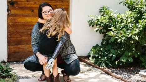 Mandie hugs her daughter outside with her bebionic hand prosthesis
