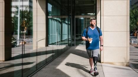 Rob walking outside with his Empower prosthesis near an office building.