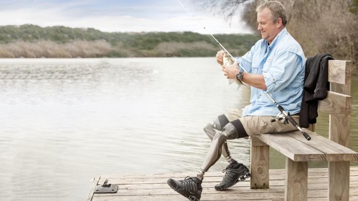 Aaron fishing by a lake while wearing his Genium knees