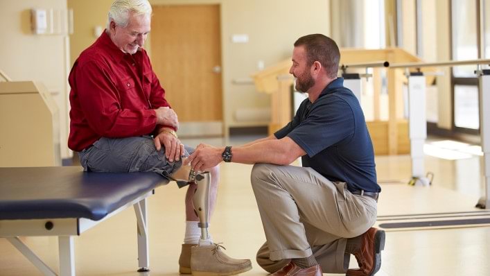 Therapist working with seated man wearing a Kenevo prosthesis